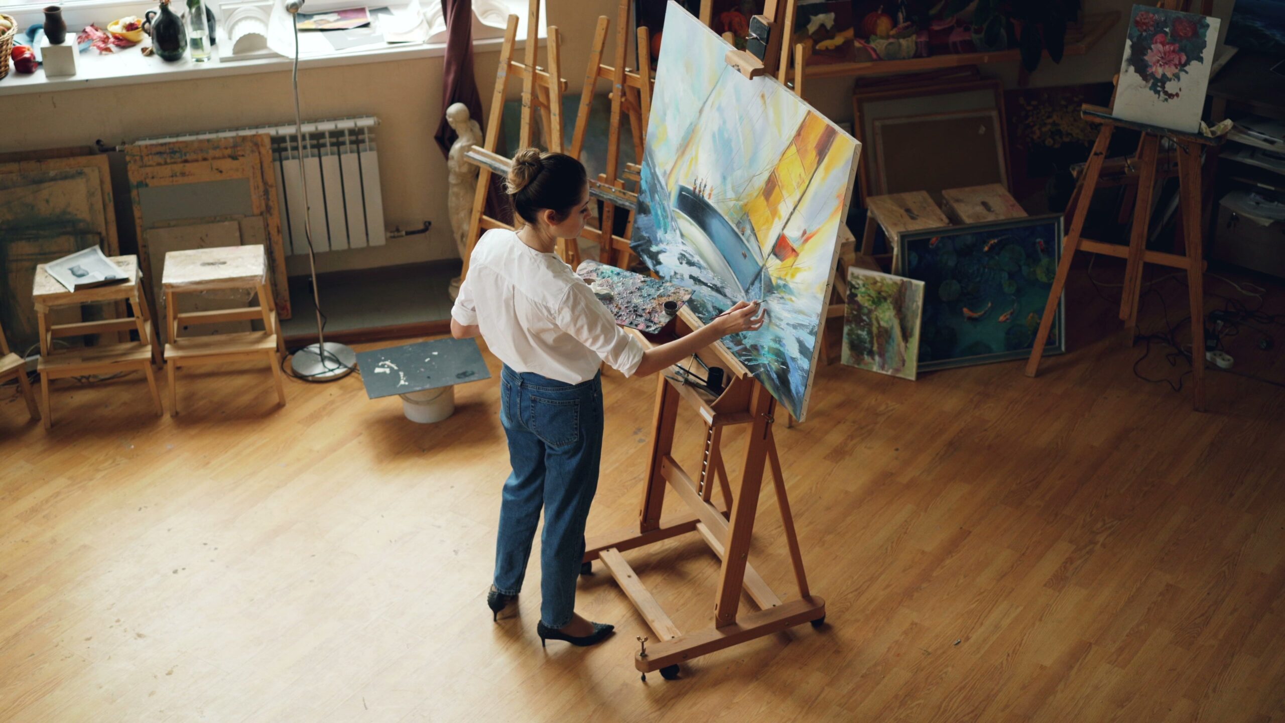 A femme presenting artist working on a seascape painting in her art studio.